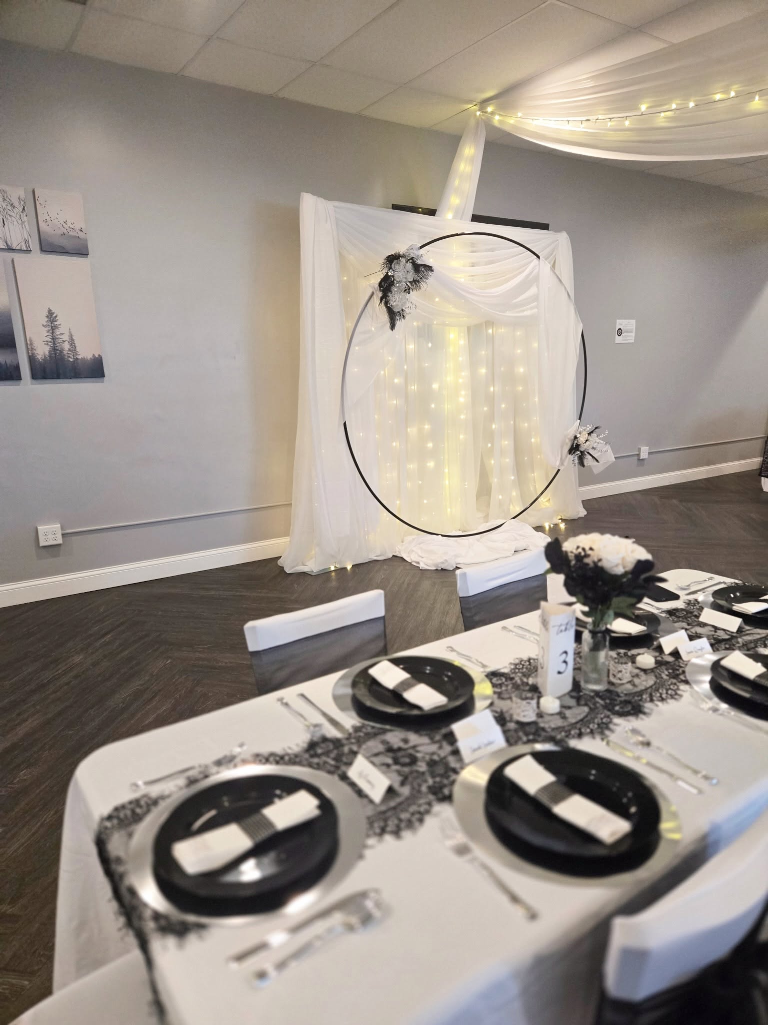 Circular backdrop with fairy lights and white drapes beside a table set with black plates