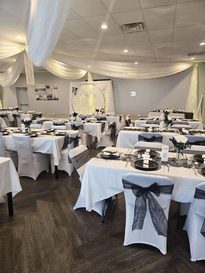 Wide view of a function hall with draped ceiling and rows of set tables